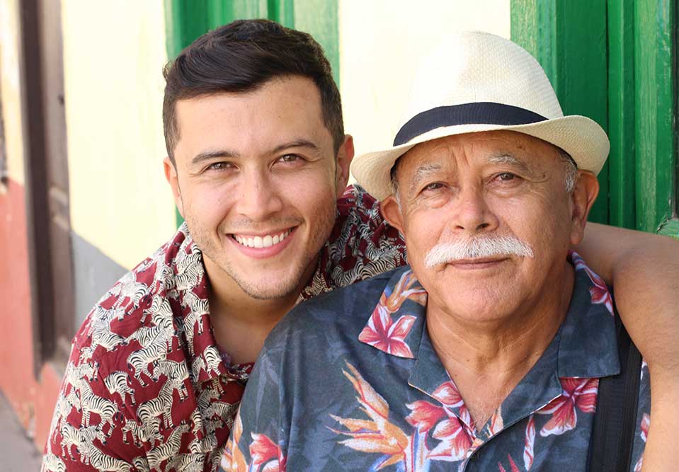 a young man with his arm around an older man smiling at the camera