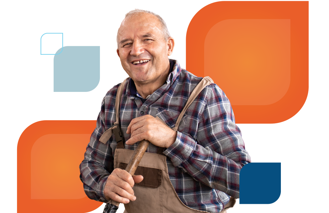 a man in overalls with a farming tool smiles at the camera
