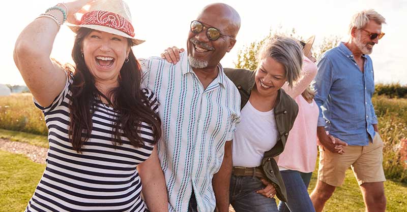 five people walking in the sun smiling and hugging
